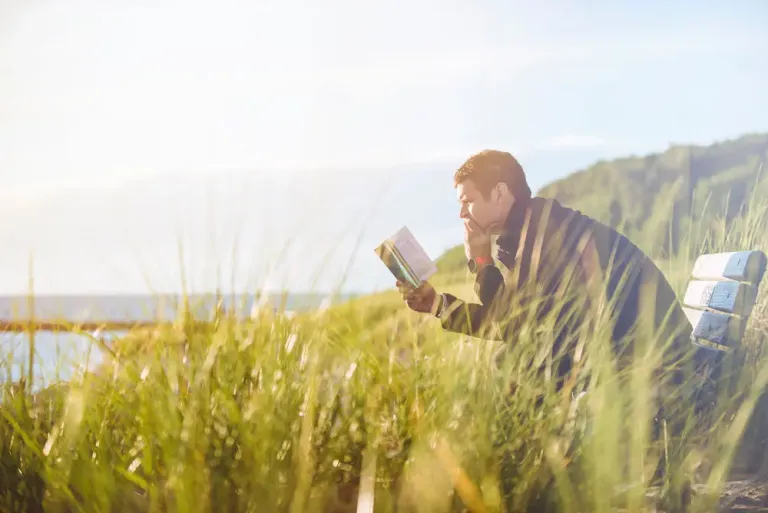 Someone reading behind the grass, near the sea